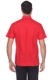 A man viewed from the back wearing a bright red short-sleeve button-up shirt and black pants, photographed against a plain white studio background.
