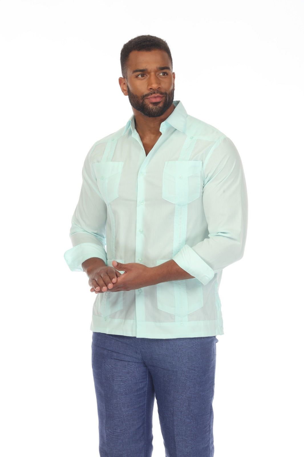 A man wearing a light mint green Guayabera-style shirt with vertical stripes and blue jeans, standing against a plain white background.