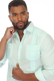A man wearing a light mint green long-sleeve button-down shirt with chest pockets, posed against a solid white background.
