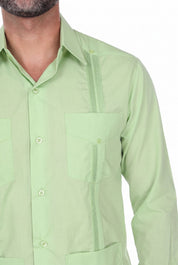 A close-up of a man wearing a light green button-up shirt with vertical channel tufting and chest pockets, shown against a plain white background.
