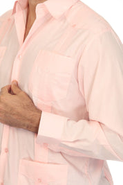 A close-up of a man wearing a light pink long-sleeve button-up shirt with a chest pocket and button cuffs, shown against a plain white background.