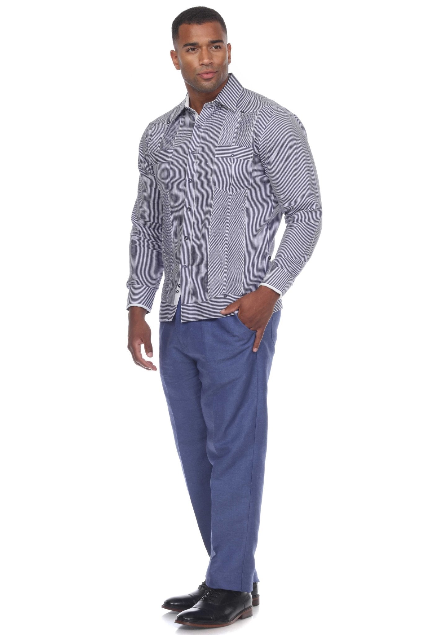 A man wears a long-sleeve, striped 100% Linen Contrast Panel Guayabera Shirt with blue pants.