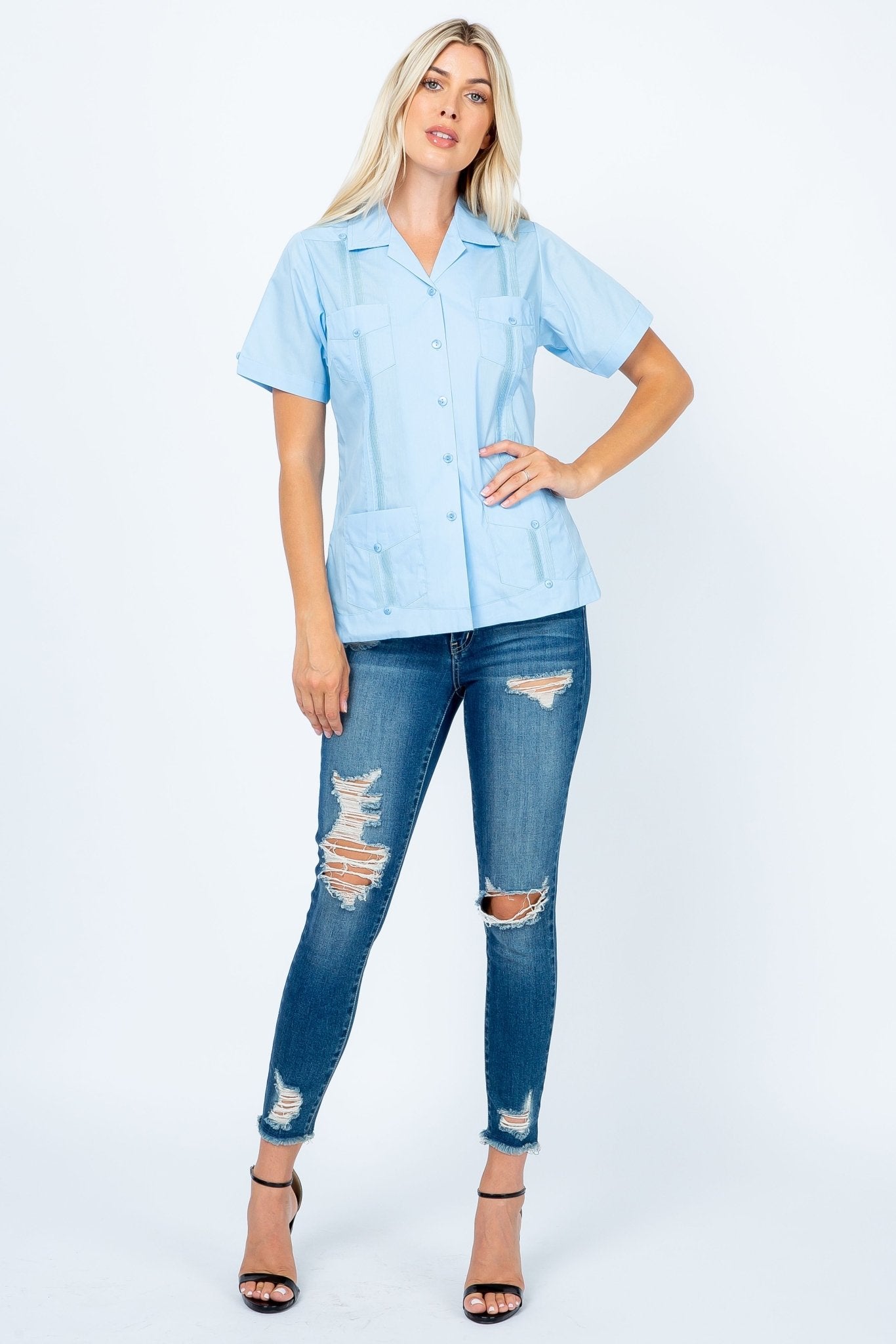 Model in a light blue Women's Short Sleeve Guayabera with 4 pockets, shown front-on, paired with jeans.