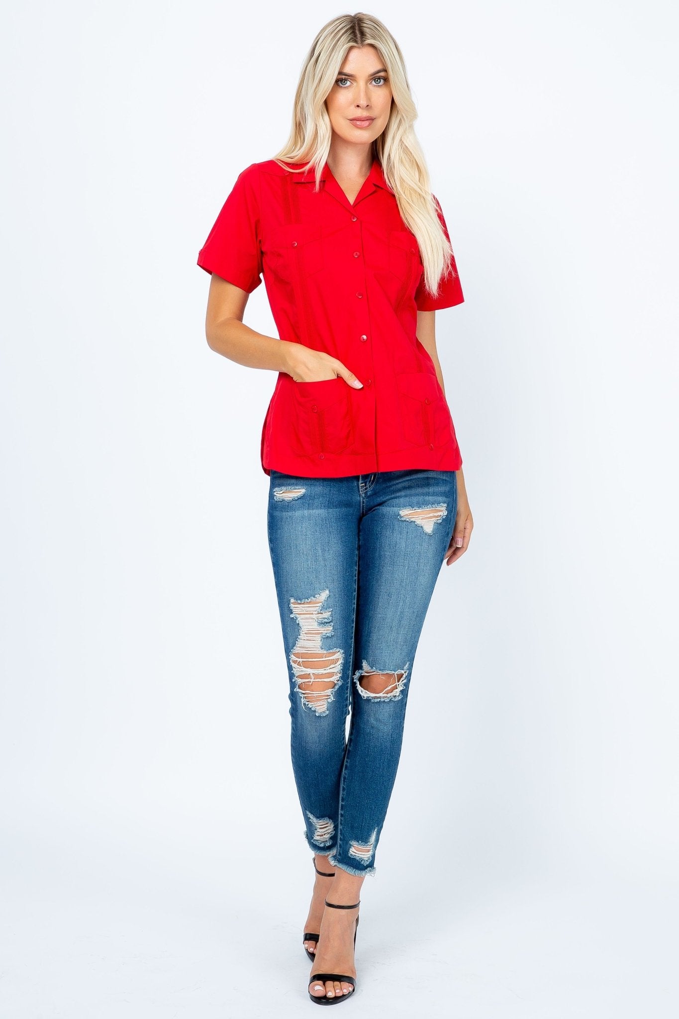 A blonde woman models a red, short-sleeve Women's Short Sleeve Guayabera with 4 Pockets, front view, hand in one pocket.