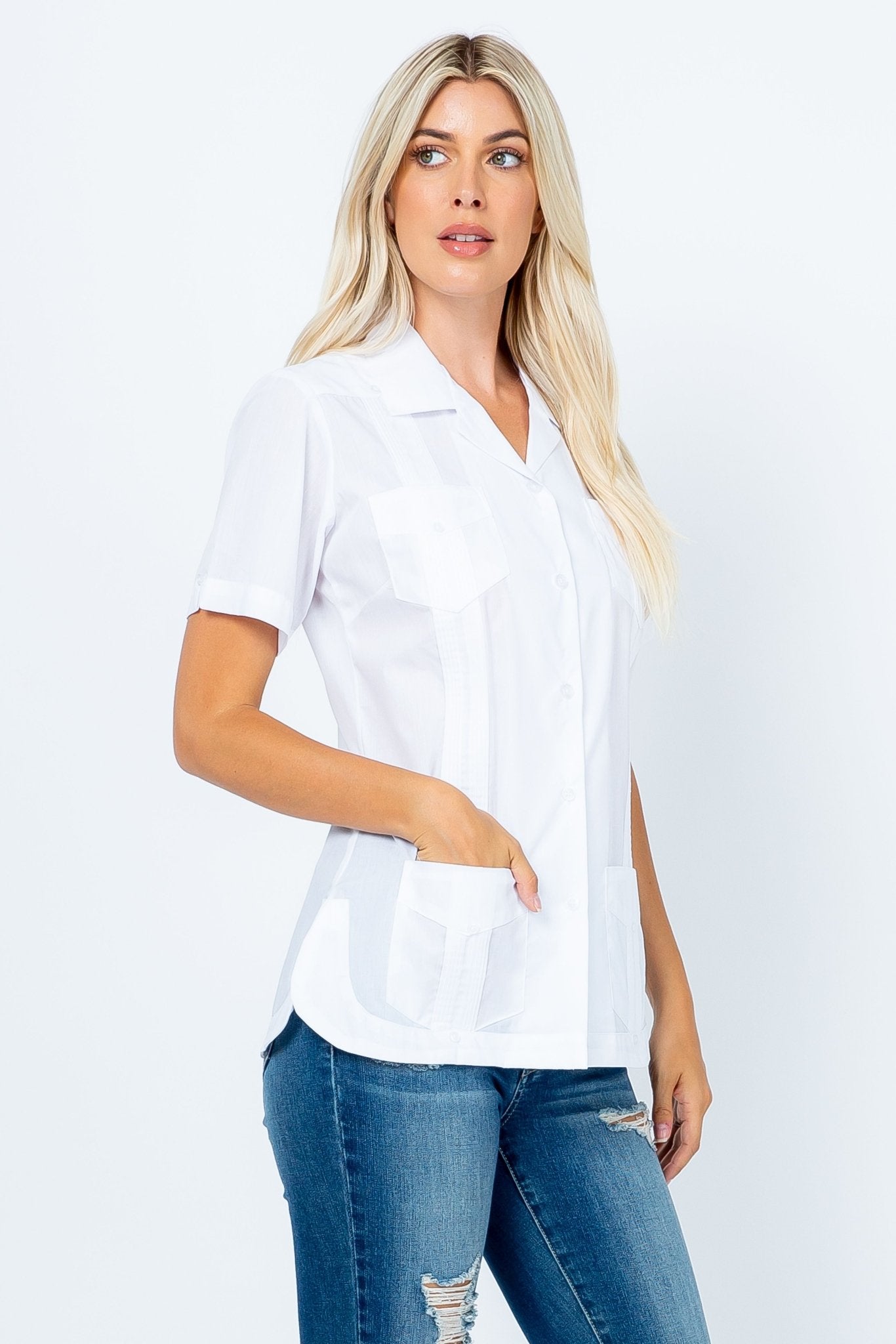 A blonde woman models a white, short-sleeve Women's Short Sleeve Guayabera with 4 Pockets, her hand in one pocket.