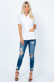 A woman models a white short sleeve Women's Guayabera with 4 Pockets, styled with blue ripped jeans.