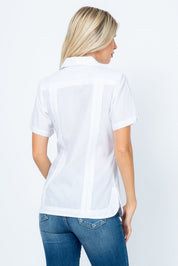 Back view of a woman wearing a white short sleeve Guayabera with vertical pintuck details.