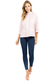 Full body view of a Light Pink Women's 100% Linen Guayabera Shirt styled with denim for a resort look.